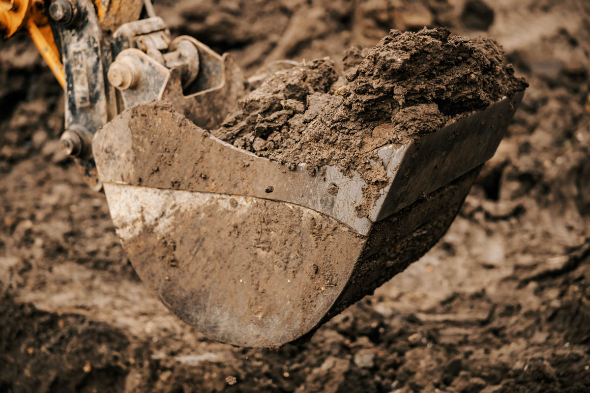 Close up of a backhoe bucket full of soil.